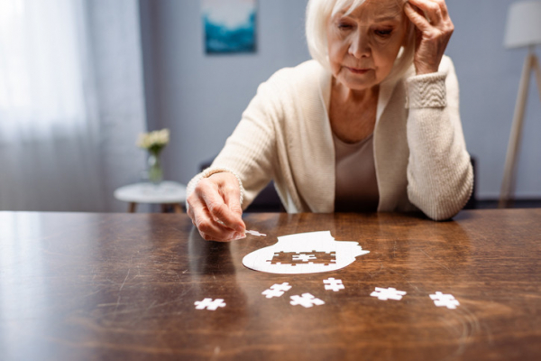senior woman assembling a jigsaw puzzle where all the pieces are blank white